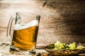 Beer mug stands on table next to hop in basket Royalty Free Stock Photo