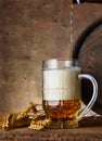 Beer mug with wheat ears and wooden barrel on a dark wall background, pour beer