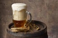 Beer mug with wheat ears on wooden barrel on a dark wall background