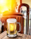 Beer mug on wooden table and copper brewing cask at the background Royalty Free Stock Photo