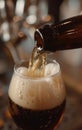 Beer is poured from dark brown bottle into beer glass. Close-up light fresh beer poured into glass. Royalty Free Stock Photo