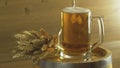 Beer is poured into a glass on the barrel near the barley