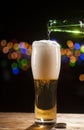 Beer is pouring into glass on bar lights background Royalty Free Stock Photo