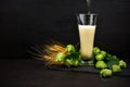 Beer pouring into a glass. Glass of beer with green hops and wheat ears on dark wooden table Royalty Free Stock Photo