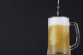 Beer pouring into a sweated mug on dark background