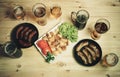 Beer, roasted potato and frying pans with grilled sausages Royalty Free Stock Photo