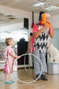 Beer-Sheva, ISRAEL -Clown inflates the balloon and girl with hoop, July 25, 2015