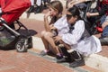 Beer-Sheva, ISRAEL - March 5, 2015:Two teenage girls sitting on the sidewalk and scarlet stroller Royalty Free Stock Photo