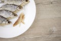 Beer snack: 4 sun-dried salted freshwater fish on a white plate - a source of vitamins and protein, a few peeled slices of meat,