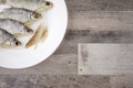 Beer snack: 4 sun-dried salted freshwater fish on a white plate - a source of vitamins and protein, a few peeled slices of meat,
