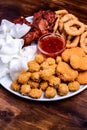 Beer snacks on the plate: chicken nuggets, onion rings in tempura, chicken popcorn, rice chips, fried chicken pieces and ketchup