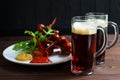 Two mugs of dark beer with delicious hot crusty grilled chicken Royalty Free Stock Photo