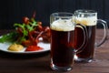 Two mugs of dark beer with delicious hot crusty grilled chicken Royalty Free Stock Photo