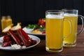 Two mugs of lager beer with crusty grilled chicken wings and var Royalty Free Stock Photo