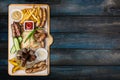 Beer snacks set. Grilled sausages and french fries with tomato and BBQ sauce, served on cutting board. Royalty Free Stock Photo