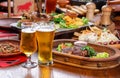 Beer table in the pub. Hot steak with sauce and vegetables. Royalty Free Stock Photo