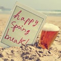 a beer and the text happy spring break in a tablet on the beach, with a filter effect Royalty Free Stock Photo