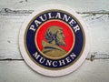 A Beermat of German beer Paulaner on the table.