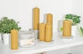 A beeswax pillar candles with traditional hex design on a shelf with various concrete and plant decor