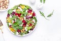 Beet, cheese and orange healthy salad with arugula, lamb lettuce, mini chard and pistachios, white kitchen table, copy space..
