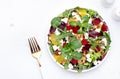 Beet, cheese and orange healthy salad with arugula, lamb lettuce, mini chard and pistachios, white kitchen table, copy space..