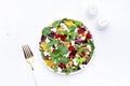 Beet, cheese and orange healthy salad with arugula, lamb lettuce, mini chard and pistachios, white kitchen table, copy space..