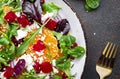 Beet, cheese and orange healthy salad with arugula, lamb lettuce, red onion, walnut and tangerine, brown kitchen table. Fresh Royalty Free Stock Photo