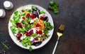 Beet, cheese and orange healthy salad with arugula, lamb lettuce, red onion, walnut and tangerine, brown kitchen table. Fresh Royalty Free Stock Photo