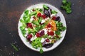 Beet, cheese and orange healthy salad with arugula, lamb lettuce, red onion, walnut and tangerine, brown kitchen table. Fresh Royalty Free Stock Photo
