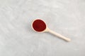 Beetroot couscous in wooden spoon on light grey background, top view. Red color couscous