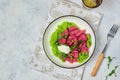 Beetroot dumplings or gnocchi with mashed green peas and curd cheese in a white plate on a light concrete background. Vegetarian Royalty Free Stock Photo