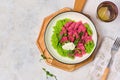 Beetroot dumplings or gnocchi with mashed green peas and curd cheese in a white plate on a light concrete background. Vegetarian Royalty Free Stock Photo