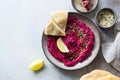 Beetroot homemade hummus on rustic plate on gray stone background