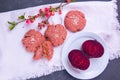 Beetroot oatmeal cookie stands on a white towel, next to a flowering branch with rose flowers, next to a white plate is cut