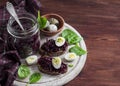 Beetroot relish and a sandwich with beets, quail egg and spinach on rustic light wooden board.