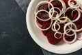 Beetroot slices with onion rings on a white plate and a dark slate background, copy space, high angle view from above Royalty Free Stock Photo