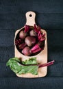 Beets with green tops in round metal pan on dark black wooden background, fresh red beetroot on backdrop kitchen table top view Royalty Free Stock Photo