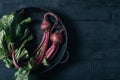 Beets with green tops in round metal pan on dark black wooden background, fresh red beetroot on backdrop kitchen table top view Royalty Free Stock Photo
