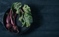 Beets with green tops in round metal pan on dark black wooden background, fresh red beetroot on backdrop kitchen table top view, Royalty Free Stock Photo