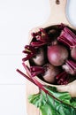 Beets with green tops in round metal pan on white wooden background, fresh red beetroot on backdrop kitchen table top view Royalty Free Stock Photo