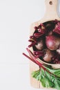 Beets with green tops in round metal pan on white wooden background, fresh red beetroot on backdrop kitchen table top view, Royalty Free Stock Photo