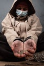 Beggar girl in a medical mask asks for help,coins in the hands of a homeless woman