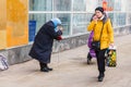 a beggar old woman begging alms in a city street. The text in Russian: jewelry salon pearls, discounts Royalty Free Stock Photo