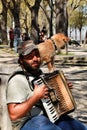 Beggar playing the accordion begging with his dog