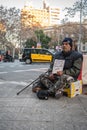 beggar sitting on a fruit box asking for money, it is dirty with a handwritten sign saying help