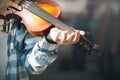 Beggar street musician is playing an old worn out violin Royalty Free Stock Photo