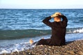 Beggarly barefooted man in suit sits back on coast