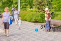 A beggarly elderly woman asks for alms on the embankment near a sculpture to Red Army soldier Sukhov Royalty Free Stock Photo