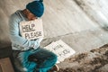 Beggars sitting under the bridge with a sign, help please