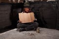 Begging homeless child sitting with a blank sign and some change Royalty Free Stock Photo